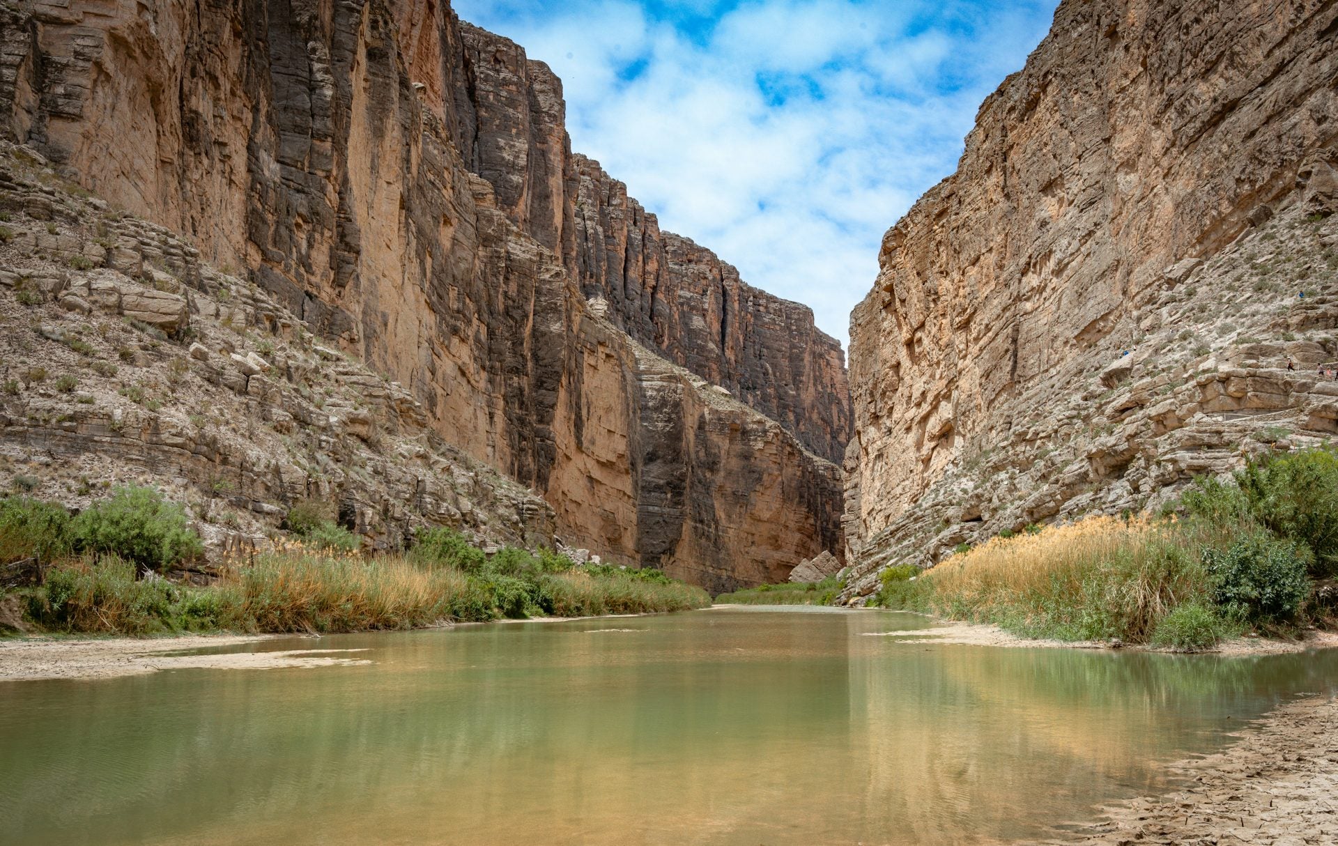 A Chihuahuan Desert canyon with the Rio Grande cutting between tall walls in hard, low sun.